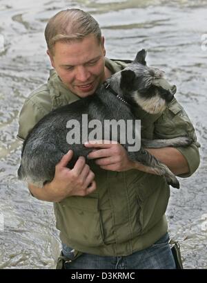 (Dpa) - ein freiwilliger trägt einen Hund wie er durch das Hochwasser in der alten Stadt Passau, Deutschland, 24. August 2005 watet. Die nahe gelegenen Flüsse Donau und Inn haben Burts ihre Ufer. Die Hochwasserwelle der Donau wird voraussichtlich geringer als zunächst befürchtet in den östlichen Teilen von Bayern. Dennoch wurden zahlreiche Hilfskräfte eingesetzt, um mobile Flut Schranken setzen Stockfoto