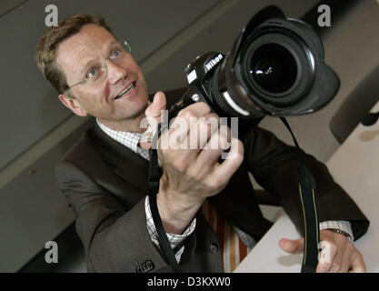 (Dpa) - Guido Westerwelle, Bundesvorsitzender der FDP, hält die Kamera eines Presse-Fotografen in seinen Händen vor einem Treffen der FDP-Bundestagsfraktion in Berlin, Dienstag, 27. September 2005. Die neue Fraktion waren zusammengekommen, die Fraktionsführer der FDP, Kopf die Partei im Deutschen Bundestag zu wählen. Aktuelle Fraktionsführer Gerhardt wird voraussichtlich bis Mai 200 im Amt bleiben Stockfoto