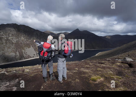Zwei Wanderer mit Blick über Ben Crom Behälter von den Hängen des Slieve Lamagan. Mourne Mountains, County Down, Nordirland. Stockfoto