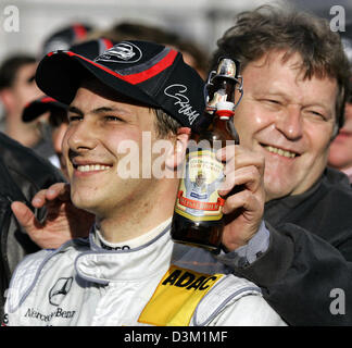 (Dpa) - Mercedes Motorsportchef, Norbert Haug (R), zeigt eine Flasche Bier mit dem Label zeigt britische Rennfahrer Gary Paffett (L) auf der Rennstrecke von Hockenheim in Hockenheim, Deutschland, Sonntag, 23. Oktober 2005. Deutscher Rennfahrer Bernd Schneider gewann das Rennen vor Briten Jamie Green und Gary Paffett (Mercedes alle). Paffett gewann den DTM-Titel. Foto: Ronald Witte Stockfoto