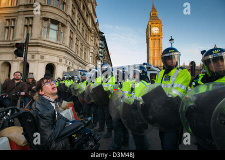 Behinderte Menschen in einem Rollstuhl, die Konfrontation mit einer Polizeiabsperrung in voller Kampfausrüstung vor der Houses of Parliament, Tag X3 Studentendemonstration, London, England Stockfoto