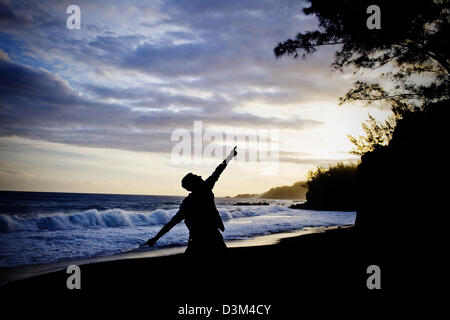 Mann posiert auf schwarzen Sand Cove bei Sonnenuntergang, östlich von Palm Hotel, Petit Ile, südlichen Insel La Réunion, Französisch, Indischer Ozean Stockfoto