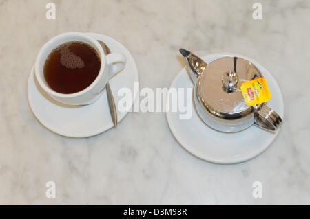 Tasse Tee und Edelstahl Teekanne Liptons auf Marmor Oberfläche Stockfoto