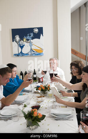 Familie sitzen um einen Tisch set für eine jüdische festliches Mahl auf Passahfest (Pessach oder Pesach transliteriert) Stockfoto