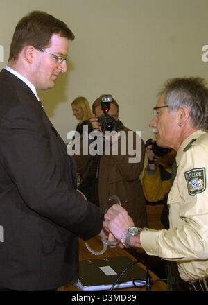 Ein Polizist zieht die Handschellen von der Beschuldigten Stefan L.at Beginn seines Prozesses in der Gerichtshalle des Landgerichts in Kempten, Deutschland, Dienstag, 7. Februar 2006. Die öffentlichen Attourney Büro wirft der ehemalige Krankenpfleger Injektion 29 Patienten mit einem Medikament cocktail zum Tode. Die 27-j hrige werden vorgeworfen, in 16 Fällen Mord, Totschlag in 12 Fällen und manslaug Stockfoto