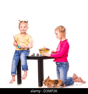 Zwei glückliche Kinder bemalen von Ostereiern isoliert auf weiss. Frohe Ostern Stockfoto