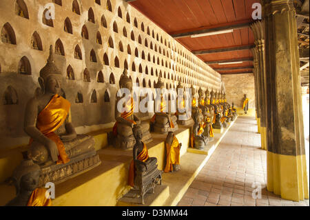 Buddha-Statuen in Safran Schärpen drapiert sitzen in Reihen unter Nischen halten kleine Buddha Figuren, in Wat Sisaket, Vientiane, Laos Stockfoto