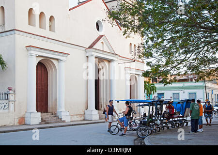 Dreirädrigen Fahrrad-taxis vor der Kathedrale von San Isidoro / Catedral de San Isidro, Parque de Las Flores, Holguin, Kuba Stockfoto