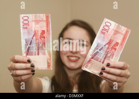 16 Jahre altes Mädchen hält zwei £100 Noten Stockfoto