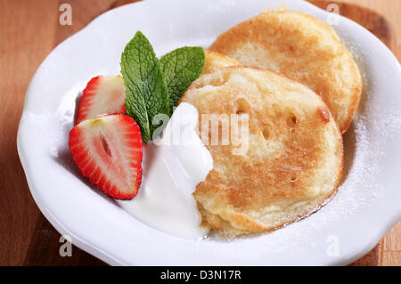 Kleine Pfannkuchen mit saurer Sahne und Erdbeeren Stockfoto