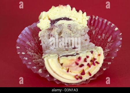 Tesco Finest leidenschaftliche Himbeer Cupcake halbieren auf rotem Hintergrund isoliert Stockfoto