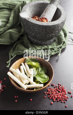 Kaffir Limetten Blätter, Zitronengras, rosa Pfefferkörner und einem Mörser und Stößel mit zerstoßenem Pfeffer. Stockfoto