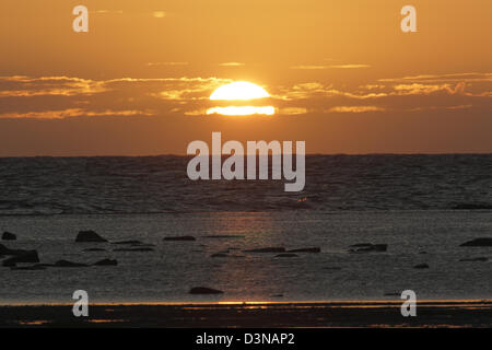 In einem goldenen Himmel über einer Stahl farbigen aufgehende Sonne Meer zeigen eine Mischung aus Welle und Meer anschwellen Bedingungen Stockfoto