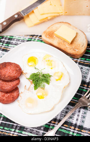 Frühstück mit gebratenen Eiern, Wurst und Toast auf weißen Teller Stockfoto