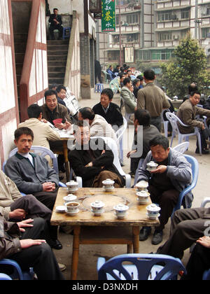 Chinesische Männer sitzen an Tischen auf der Terrasse eines Teehauses, trinken Tee und Spielkarten in Chongqing, China, 2006. Teetrinken in Teehäusern, noch Männersache in China umfasst traditionell Tabak, Spielkarten und Mahjong-Token. Chongqing ist die größte Stadt der Welt mit 31 Millionen Einwohnern und einem Durchschnitt von 200 Nebeltage jährlich. Foto: Reichardt Stockfoto