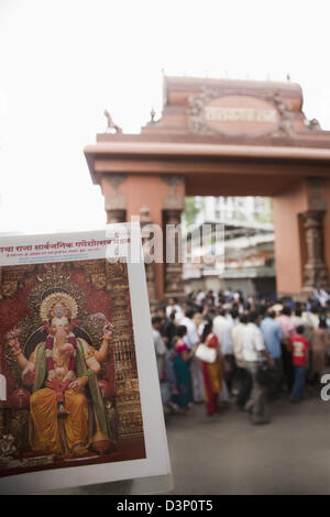 Plakat von Lord Ganesh mit Publikum in einem Tempel in den Hintergrund, Mumbai, Maharashtra, Indien Stockfoto