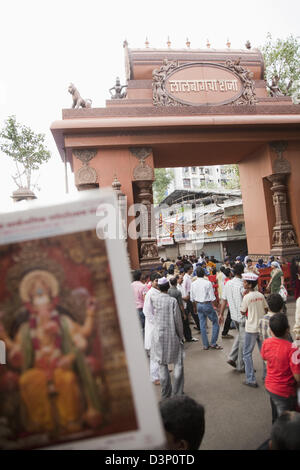 Plakat von Lord Ganesh mit Publikum in einem Tempel in den Hintergrund, Mumbai, Maharashtra, Indien Stockfoto