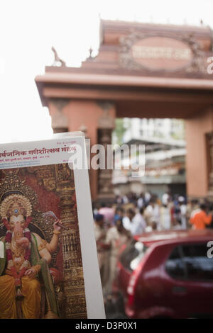Plakat von Lord Ganesh mit Publikum in einem Tempel in den Hintergrund, Mumbai, Maharashtra, Indien Stockfoto