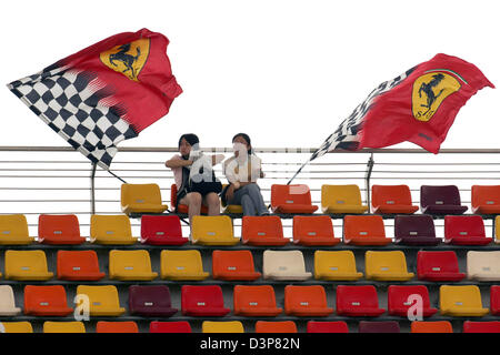 Zwei chinesische Zuschauer sitzen neben Ferrari Fahnen auf dem Shanghai International Circuit in der Nähe von Shanghai, China, Freitag, 29. September 2006. Die 2006 Formel 1 Grand Prix von China findet am Sonntag, 1. Oktober 2006. Foto: Gero Breloer Stockfoto
