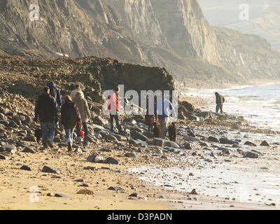 Fossilen Jäger klettern über die Felsen am Strand von Charmouth Stockfoto