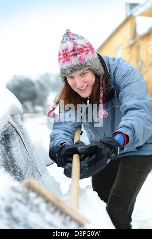 Eine Autofahrer löscht Schnee aus ihrem Auto in das Dorf von Badminton Gloucestershire UK Stockfoto