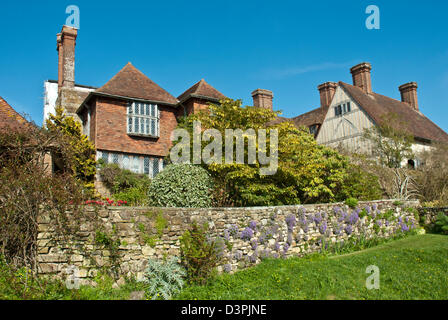 Great Dixter historischen Haus und Garten, blaue Frühling, Himmel, Tulpen und Sträucher. Graben-Bereich und Haus Stockfoto