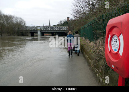 Rückansicht eines Paares mit einem Kinderwagen, der zu Fuß zu kämpfen hatte Entlang eines Pflasters auf dem überfluteten Fluss Severn Shrewsbury in Shropshire England GB KATHY DEWITT Stockfoto