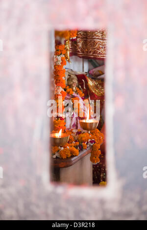 Brennendes Öl-Lampen in einem Tempel gesehen durch einen Schlitz in der Wand, Chandi Tempel, Haridwar, Uttarakhand, Indien Stockfoto