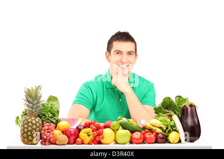 Junger Mann posiert mit einem Haufen von Obst und Gemüse, isoliert auf weißem Hintergrund Stockfoto