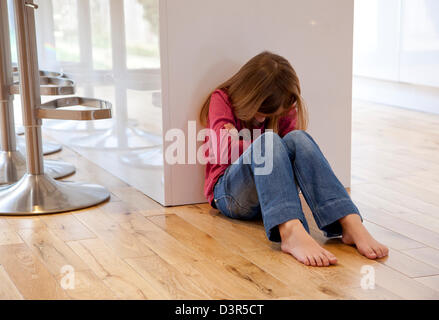 Junges Mädchen saß auf dem Boden unglücklich Stockfoto