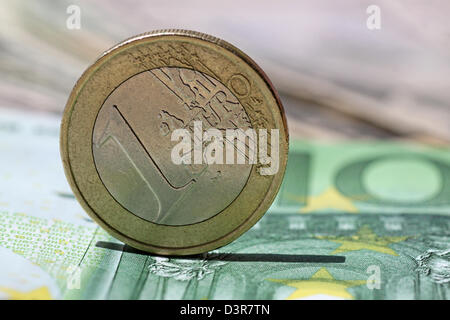 ein-Euro-Münze auf 100 Euro-banknote Stockfoto