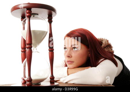 Junge Frau, die auf eine große Sanduhr Stockfoto