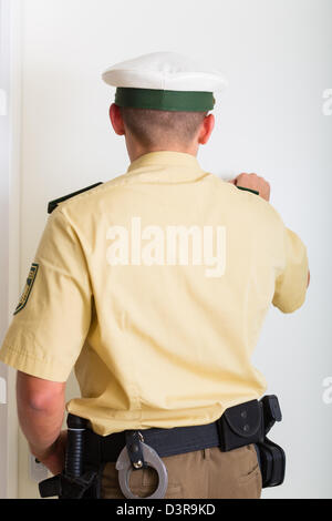 Polizist klopft an die Haustür des Hauses Stockfoto