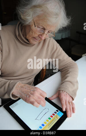 77 Jahre alte Großmutter spielen der Auslosung etwas Spiel auf einem Apple Ipad. Stockfoto