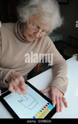 77 Jahre alte Großmutter spielen der Auslosung etwas Spiel auf einem Apple Ipad. Stockfoto