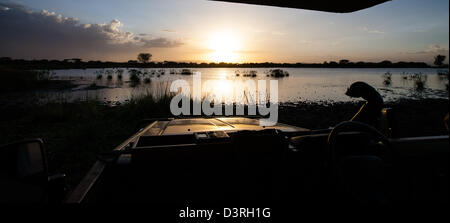 Sonnenuntergang über einem See im Serengeti Nationalpark wie aus dem Inneren eines Safari camp Autos gesehen. Tansania Stockfoto