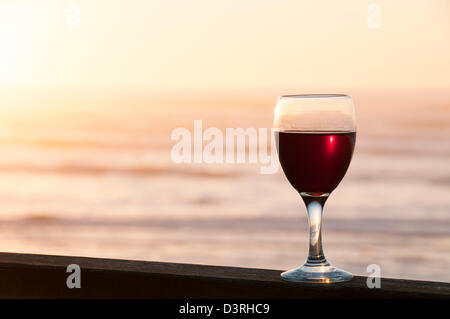 Glas Rotwein auf Deck Geländer des Hauses am Strand im Ruhestand an der zentralen Küste Oregons. Stockfoto