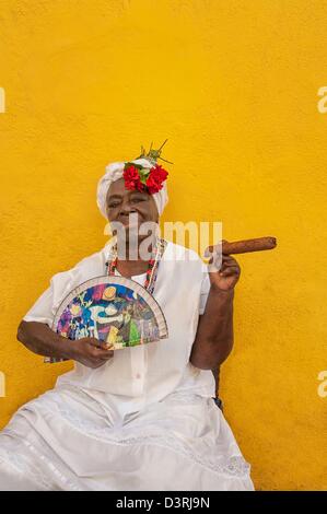 Überschrift Raum kubanische Frau afrikanischer Herkunft tragen weiße Tracht posiert in Alt-Havanna mit Zigarre & Lüfter in Hand Kuba Stockfoto