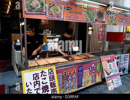 Beliebter Snack namens Takoyaki, Kugeln aus Teig mit Tintenfisch Fleisch innen, zum Verkauf stand im trendigen Dotonbori, Osaka, Japan. Stockfoto