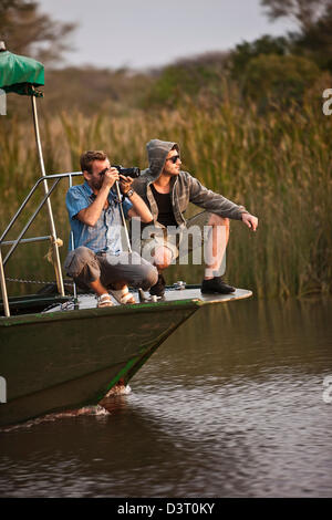 Fotografen, die Bilder von einem Boot in Phinda Game Reserve, Südafrika Stockfoto