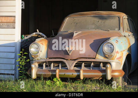 Auto aus dem Jahr 1950 in einer alten Garage, a1952 rostig und verlassenen Sitzung Studebaker in Abend Sonne. Stockfoto