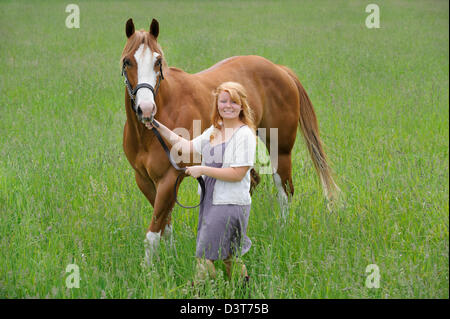 Junge Frau Pferd durch Wiese, eine 18 Jahre alte rote behaarte Reiterin führt. Stockfoto