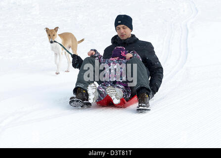 Vater und Tochter Schlitten fahren im winter Stockfoto