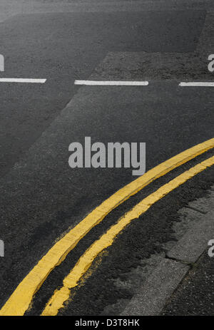 Gebogene doppelte gelbe Linien auf der Straße an einer Kreuzung, UK Stockfoto
