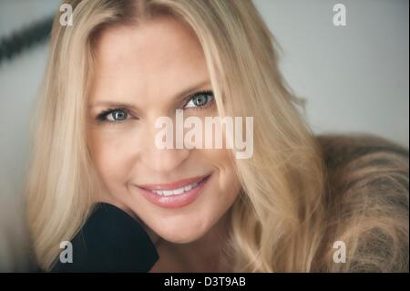 Kopfschuss schön blond blaue Augen Frau mittleren Alters befasst sich mit Kamera trug schwarz-top Stockfoto