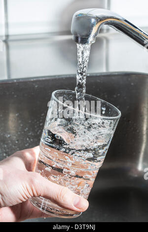 Wasser läuft in einem Glas, aus einem Wasserhahn in der Küche. Stockfoto