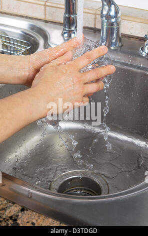 Vertikale Foto von weiblichen Händen ein Trinkglas mit Wasser vom Wasserhahn Spüle spülen Stockfoto