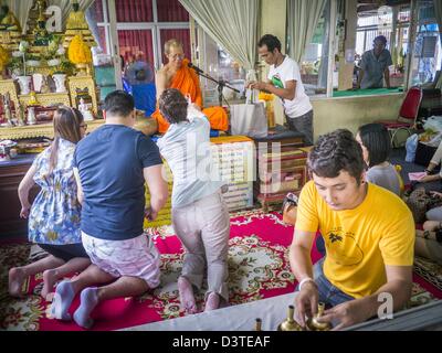 24. Februar 2013 - Bangkok, Thailand - A Family Segnungen empfängt ein buddhistischer Mönch in Wat Hua Lamphong. Wat Hua Lamphong ist ein Royal buddhistischer Tempel, dritte Klasse, in der Bang Rak Viertel von Bangkok, Thailand. Es befindet sich an der Rama IV Road, etwa 1 km von der Stadt Hua Lamphong Hauptbahnhof. Ein Eingang zu Sam Yan Station auf der Bangkok Metro (u-Bahn) befindet sich vor dem Haupteingang des Tempels Verbindung auf Rama IV. Wat Hua Lamphong wurde 1996 anlässlich des 50. Jahrestages der Aufstieg auf den Thron von König Bhumibol Adulyadej (Rama IX) im Jahr 1996 renoviert. Das royal Stockfoto