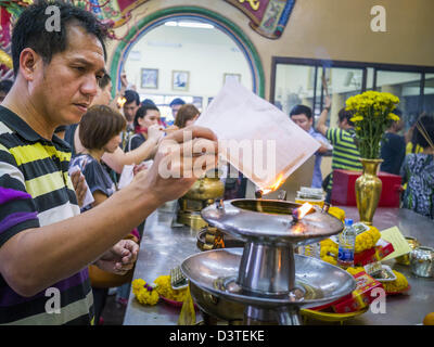 24. Februar 2013 - Bangkok, Thailand - beten und Zettel zu verbrennen, nachdem '' machen Verdienst '' durch den Kauf von für Bedürftige im '' Sarg Tempel '' der Ruamkatanyu-Stiftung neben Wat Hua Lamphong Särgen. Die Ruamkatanyu-Stiftung bietet Särge Bangkoks mittellosen und Notfall medizinische Dienstleistungen für Unfallopfer in Bangkok. Wat Hua Lamphong ist ein Royal buddhistischer Tempel, dritte Klasse, in der Bang Rak Viertel von Bangkok, Thailand. Es befindet sich an der Rama IV Road, etwa 1 km von der Stadt Hua Lamphong Hauptbahnhof. Ein Eingang Sam Yan-Station auf der Bangkok metro Stockfoto