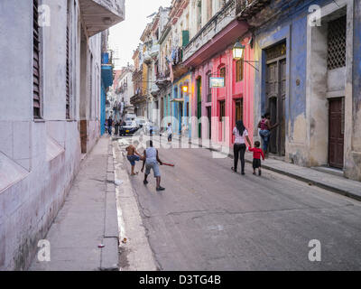 Kinder spielen Baseball in der Straße in Havanna, Kuba mit bunten alten kolonialen Gebäude entlang der schmalen Straße. Stockfoto